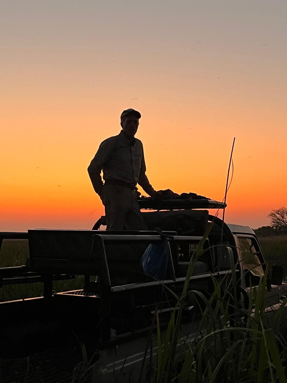 Hunter silhouetted standing in the vehicle at sunset on the Zambezi Delta, Mozambique