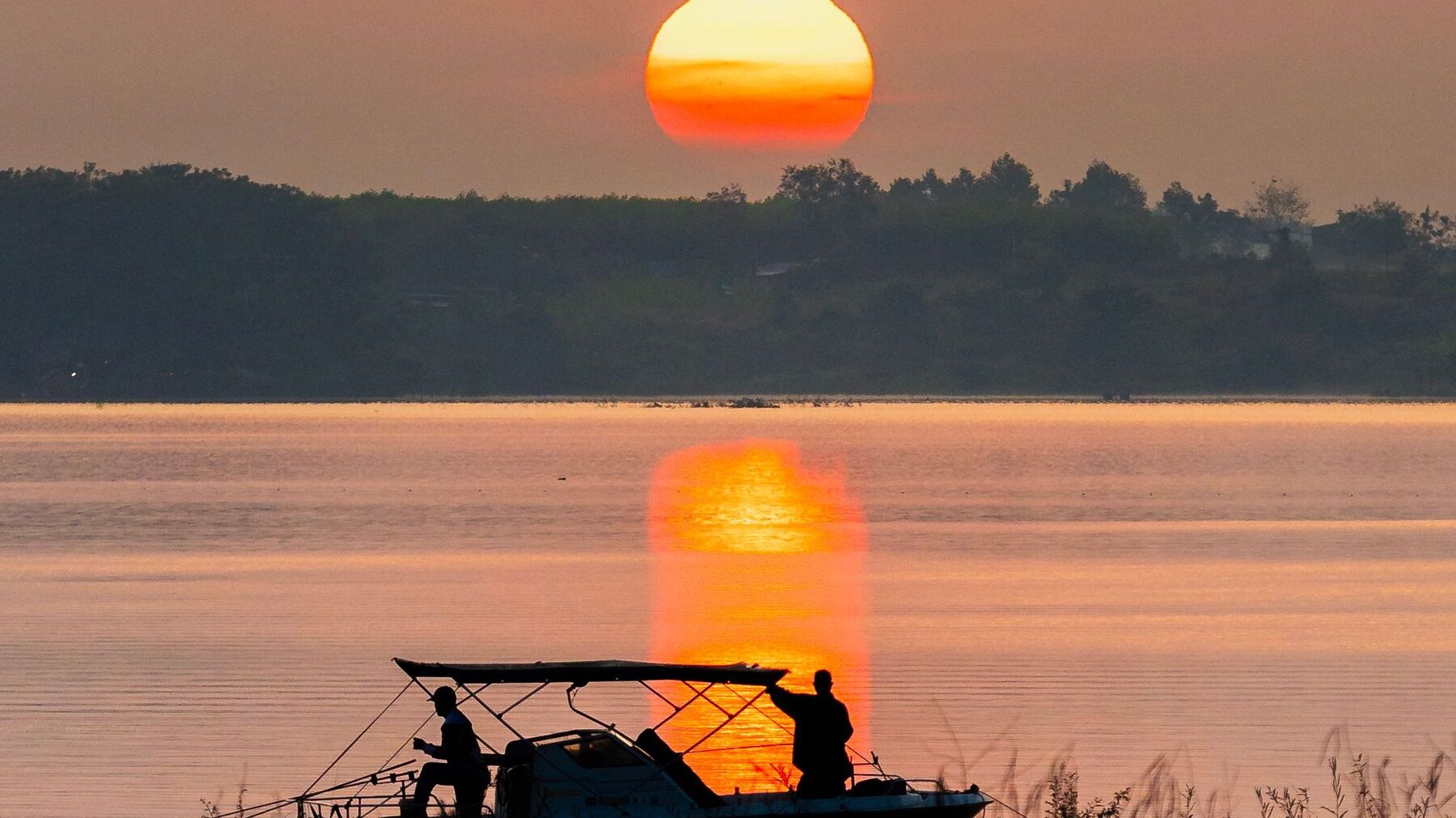 Fishing boat silhouetted against the sunset on the Zambezi, tiger fishing water