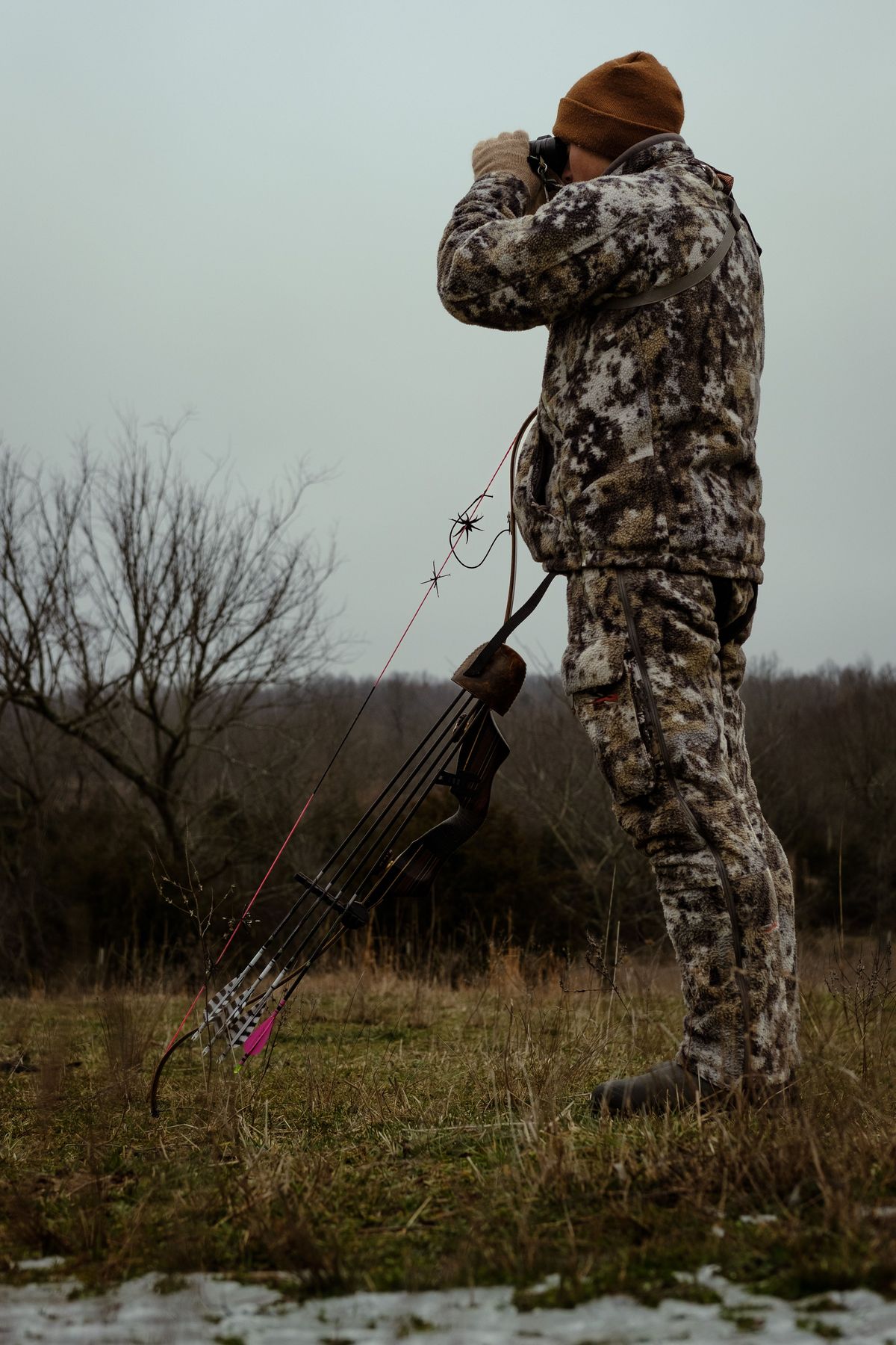 Bow hunter in full camouflage glassing for plains game in Limpopo, South Africa