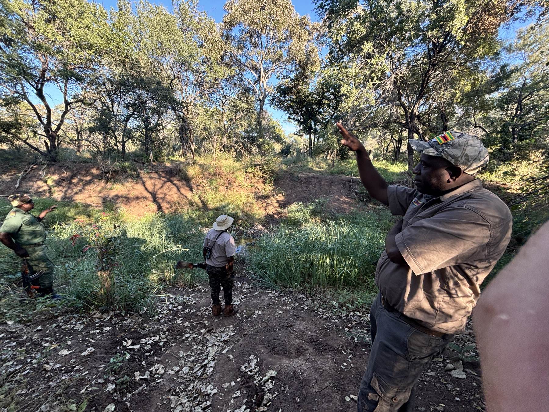 Trackers reading sign in a dry riverbed with the hunting party, Zimbabwe