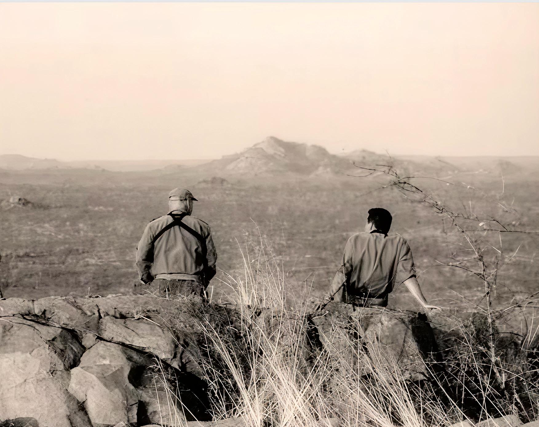 Professional hunter and tracker glassing for game from a rocky ridge in Zimbabwe with Nhoro Safaris