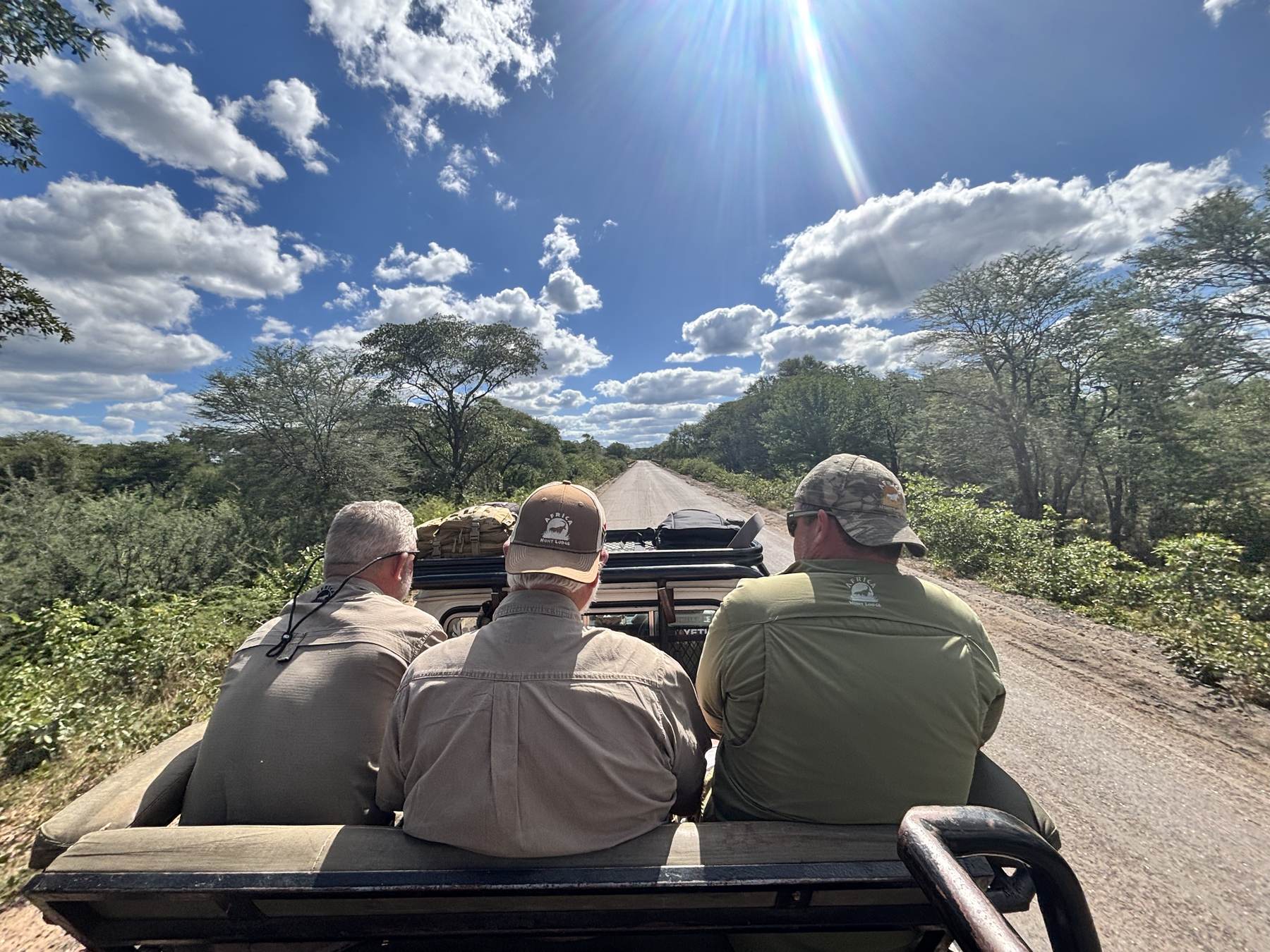Hunting party riding the vehicle down a cutline at the start of a day, Zimbabwe