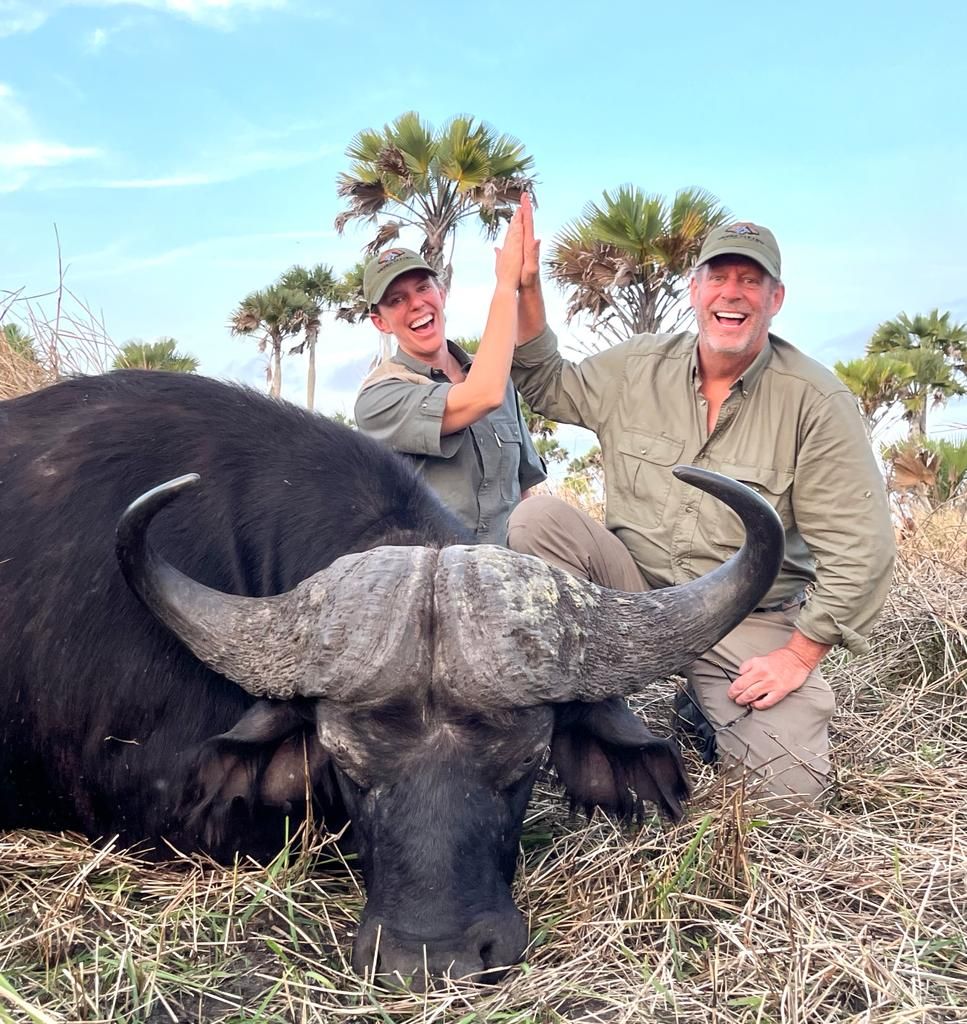 Hunting clients celebrating a Cape buffalo bull under Delta palms, Mozambique