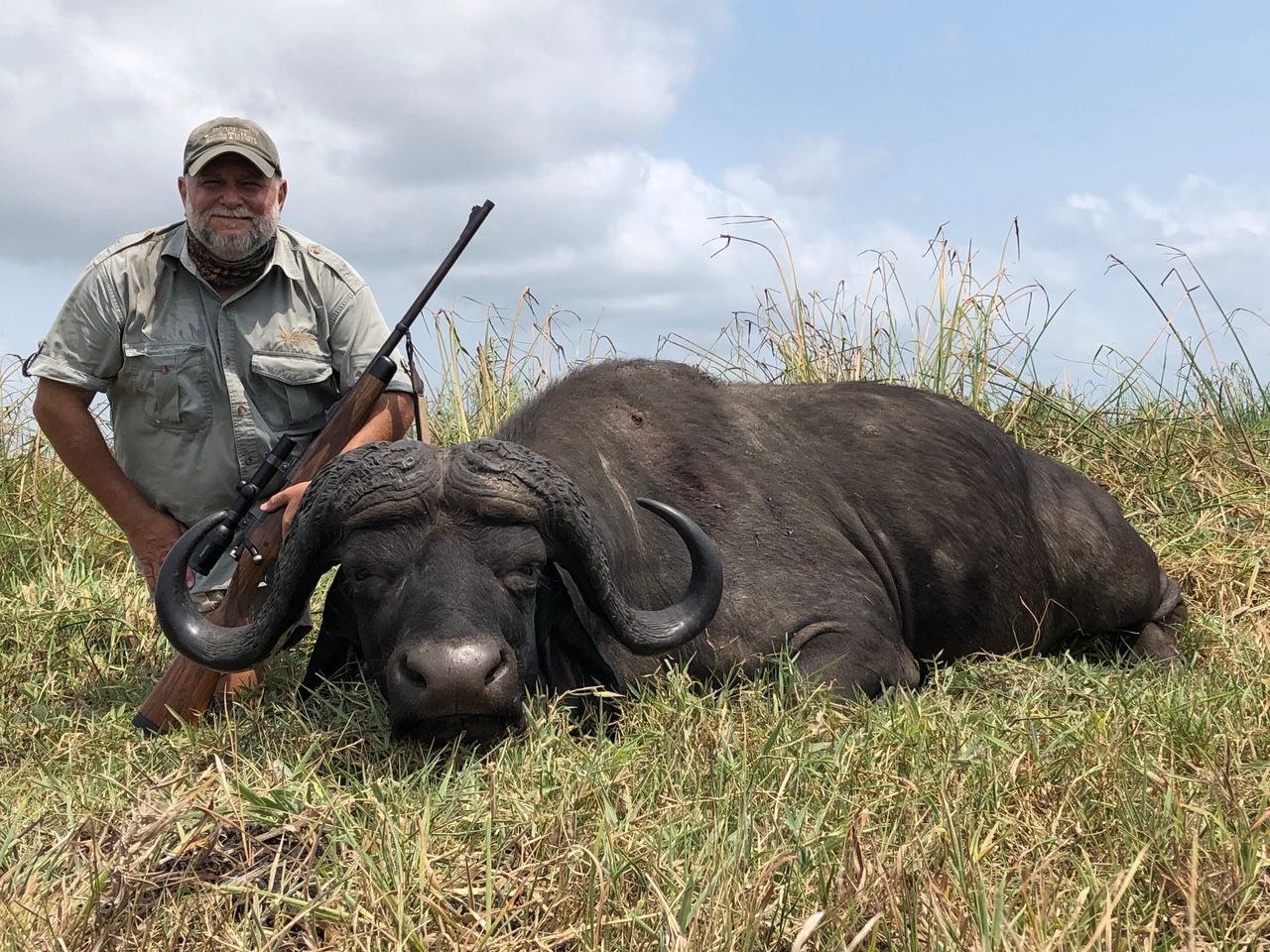Hunting client with a Cape buffalo bull in Delta grass, Zambezi Delta, Mozambique