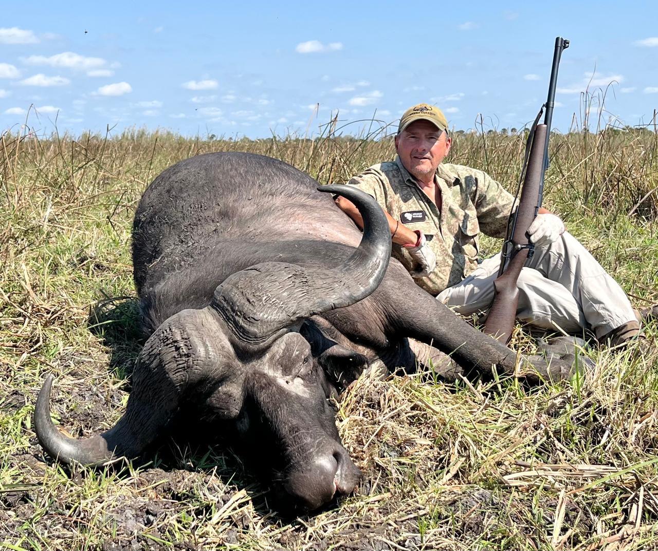 Hunter with his rifle beside a Cape buffalo bull, Zambezi Delta, Mozambique
