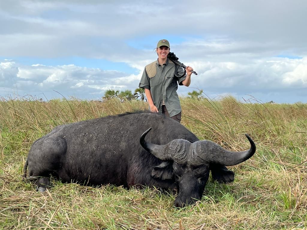 Hunter standing behind a Cape buffalo bull with Delta palms on the horizon, Mozambique