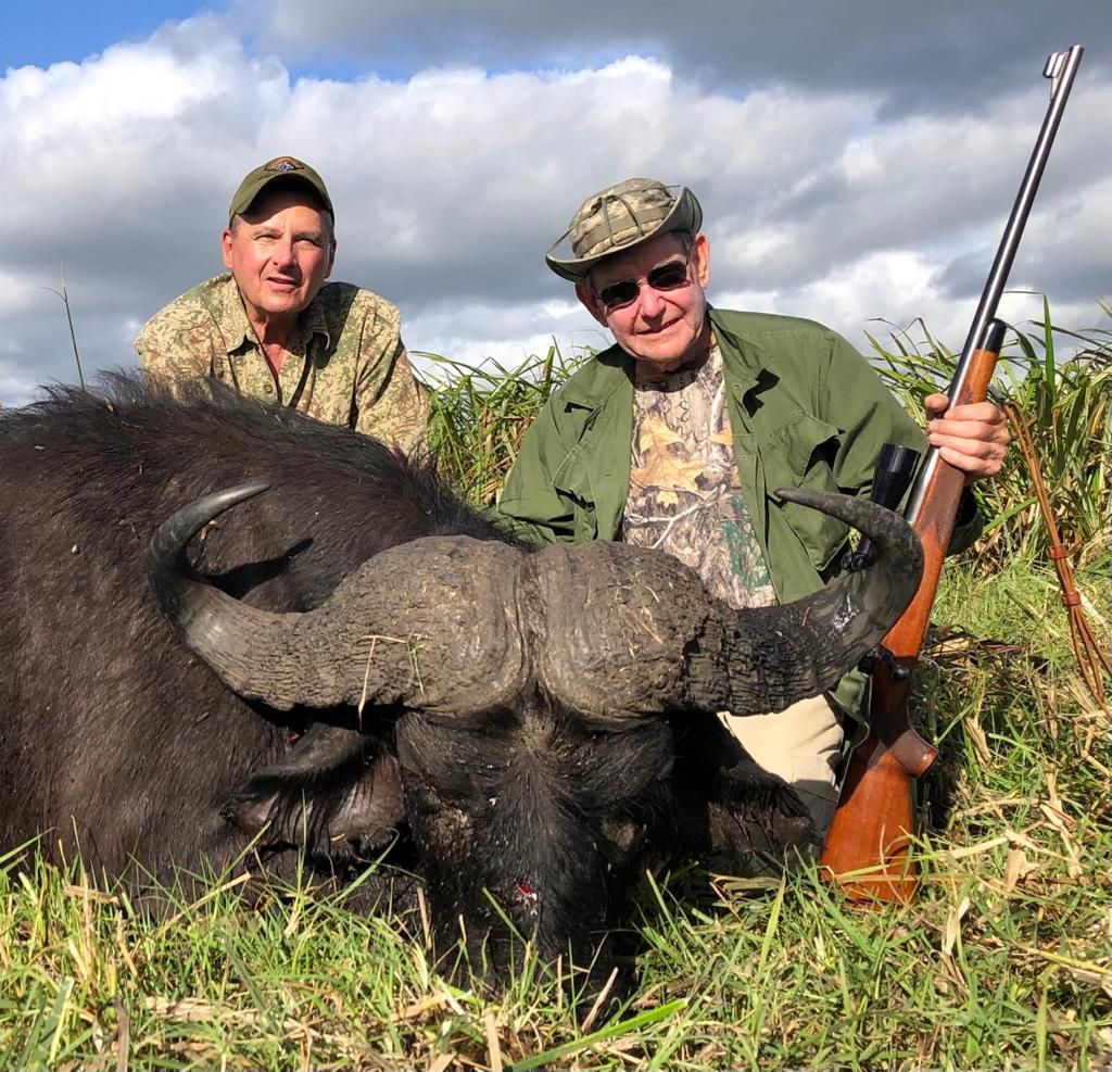 Two hunting clients with a Cape buffalo bull and rifle, Zambezi Delta, Mozambique