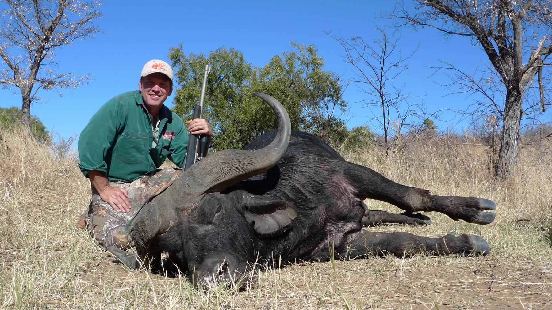 Hunter with a Cape buffalo bull taken in dry winter bushveld, Zimbabwe