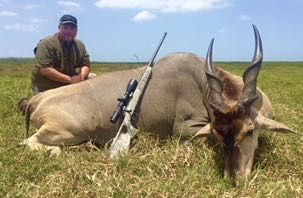 Hunting client with an eland bull taken in open woodland, Zimbabwe
