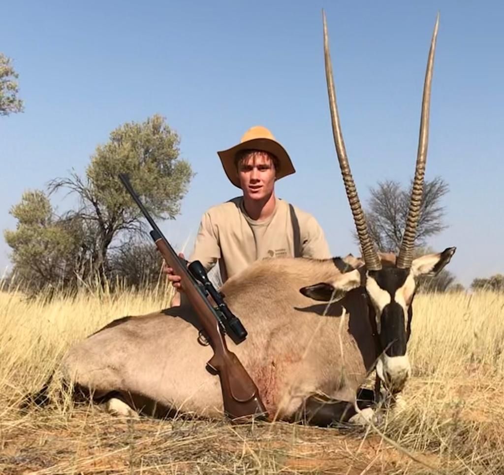 Young hunter with a gemsbok bull taken in Kalahari grassland, South Africa