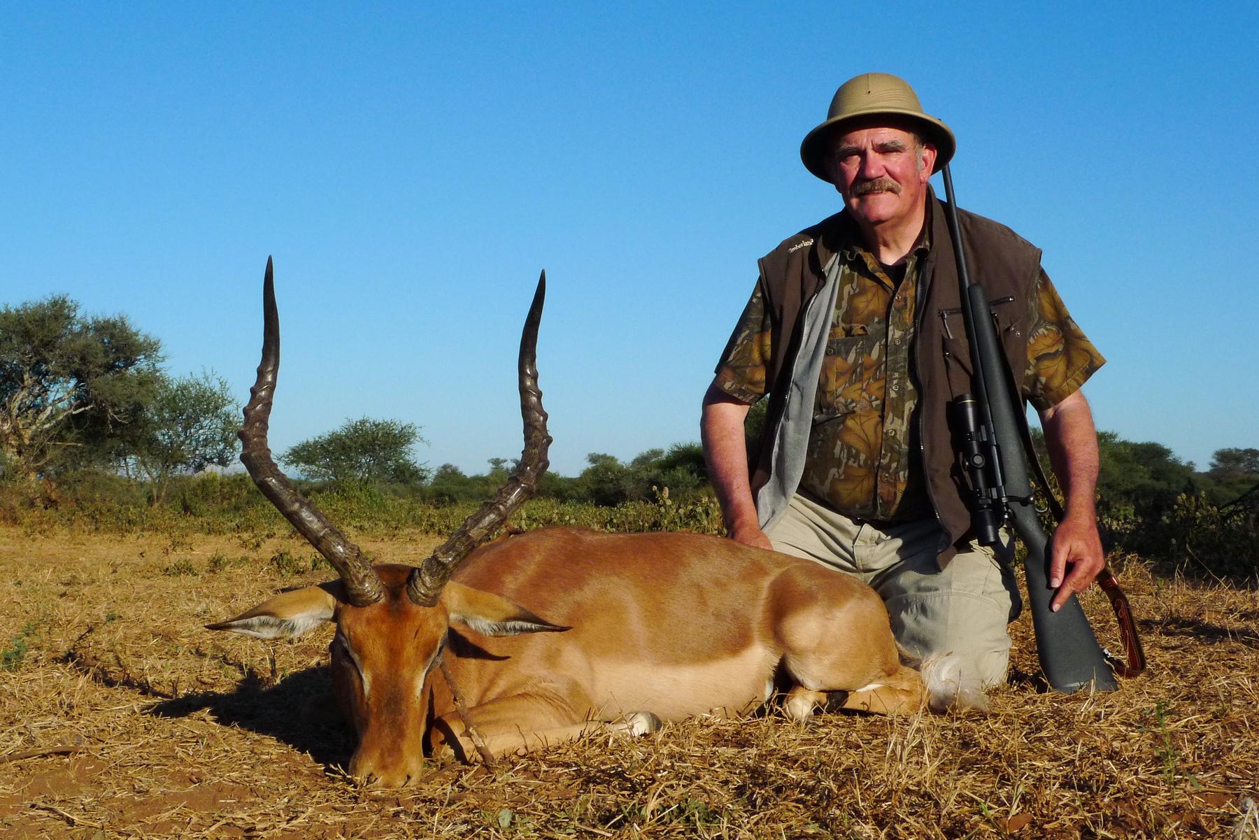 Hunter with an impala ram taken in dry grass, Limpopo, South Africa