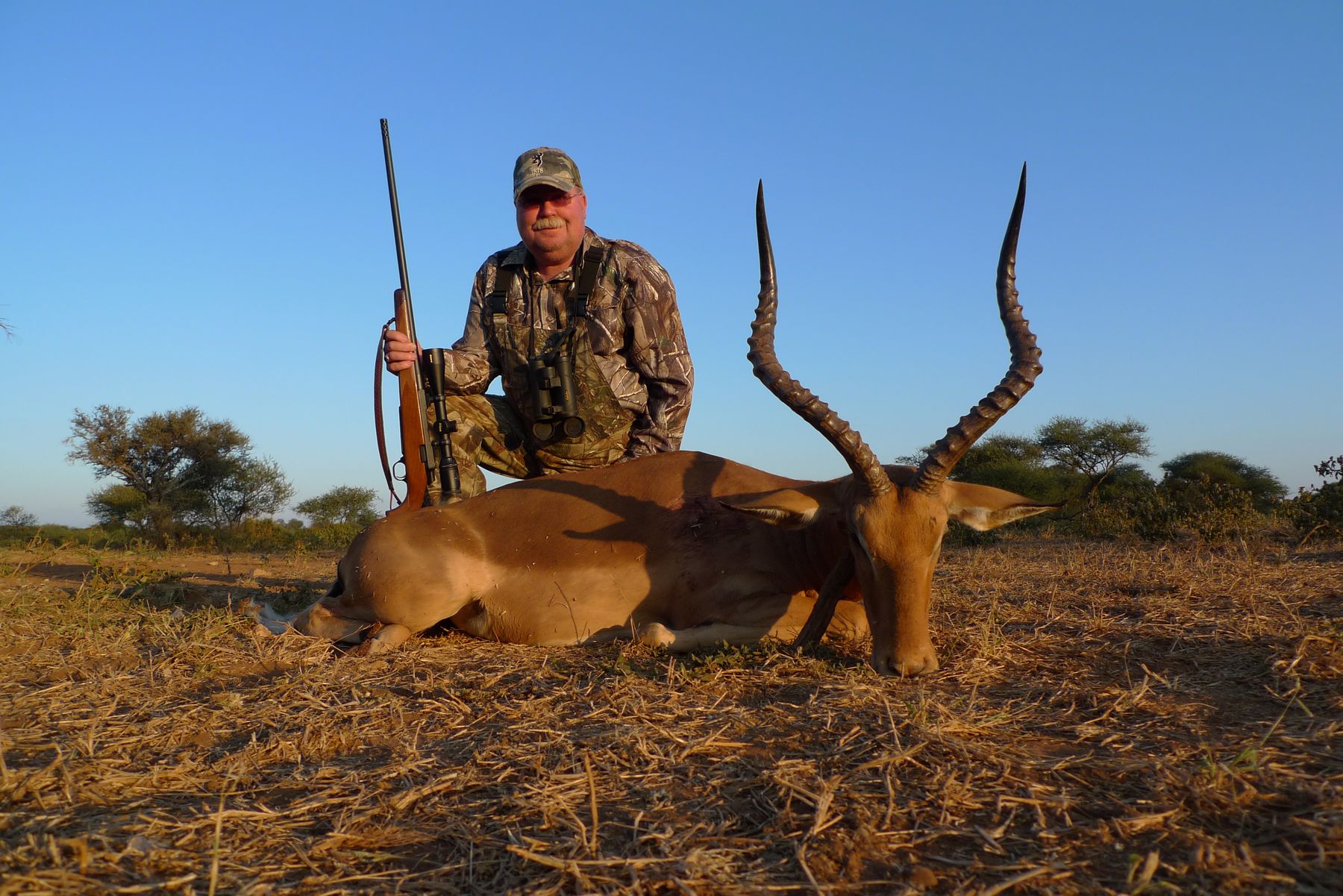 Hunting client with an impala ram taken in dry grass, South Africa
