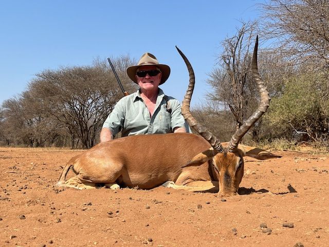 Hunting client with an impala ram taken on red sand, South Africa