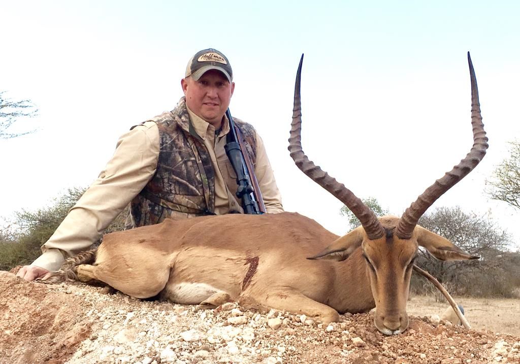 Hunter with his rifle beside an impala ram taken in Limpopo, South Africa