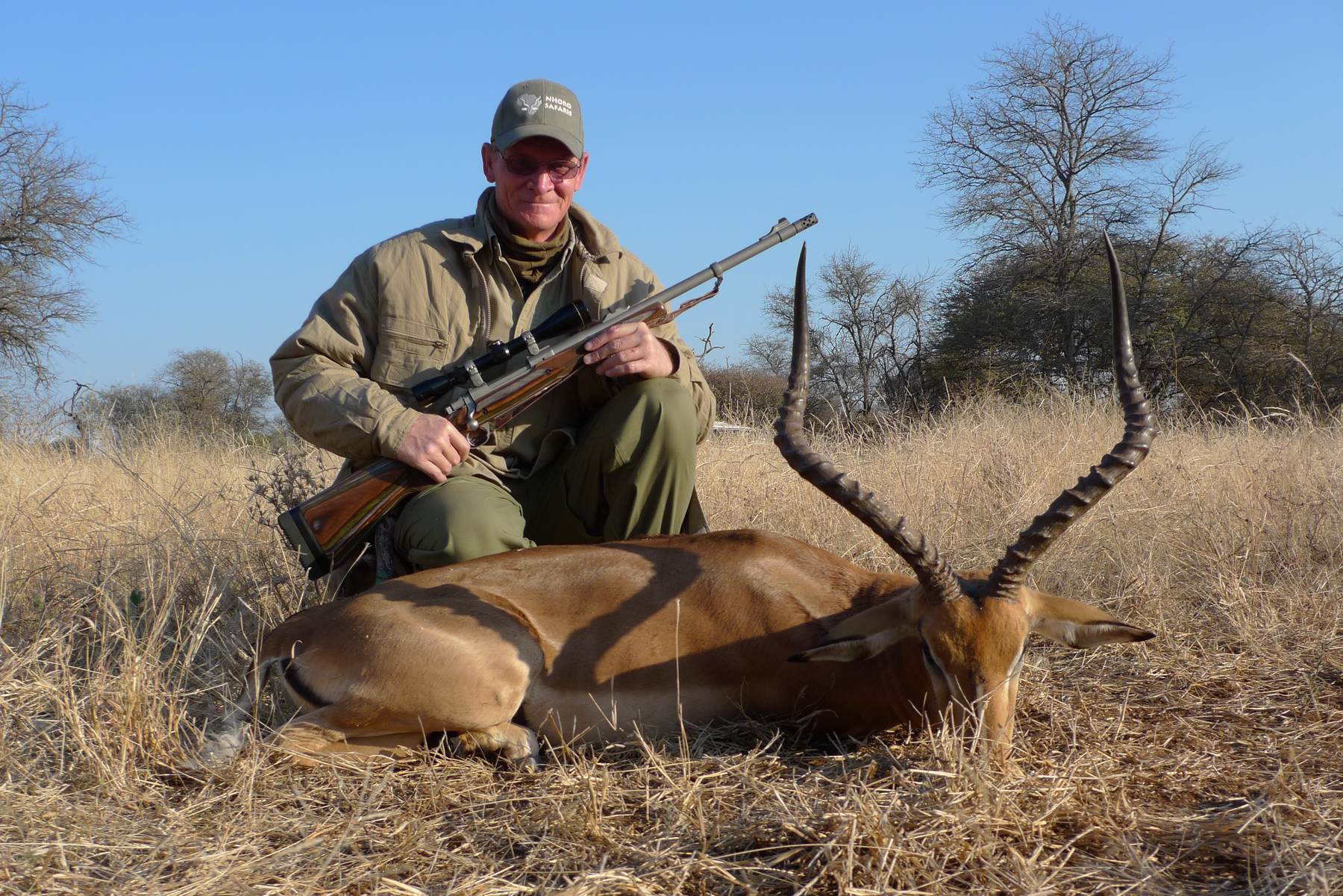Hunter with an impala ram taken in winter bushveld, Limpopo, South Africa