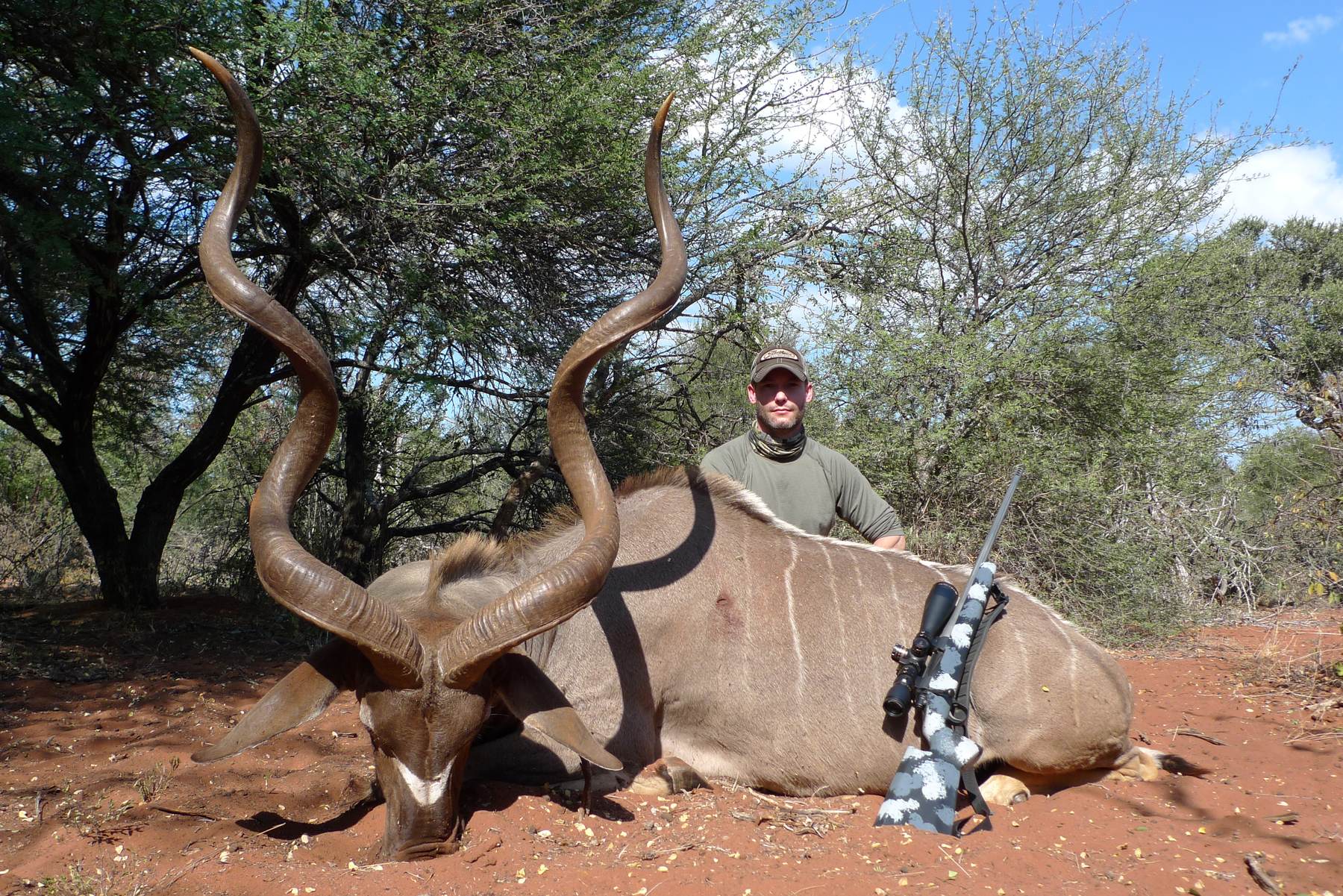 Hunting client with a kudu bull taken on red soil, South Africa