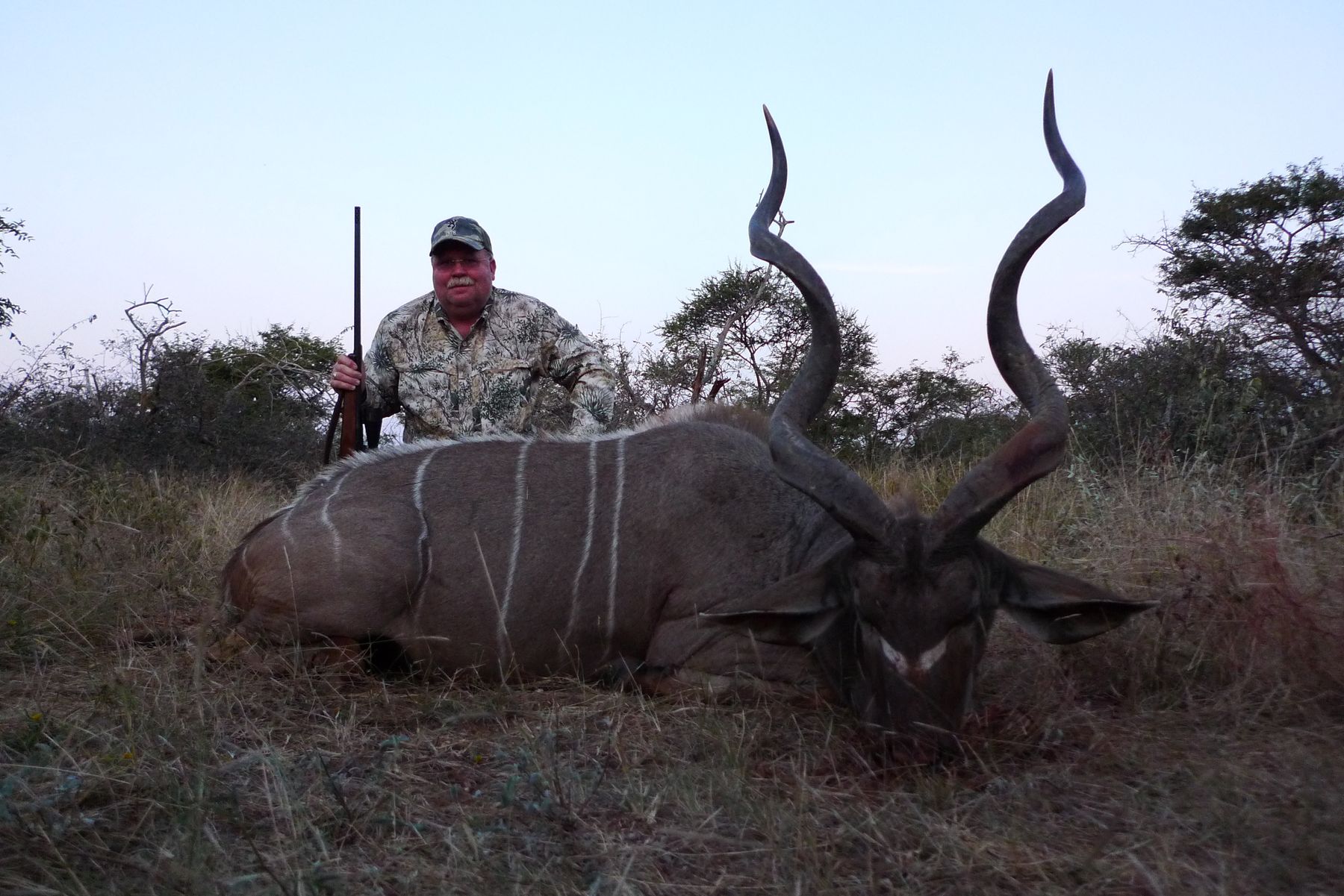 Hunter with a kudu bull taken in winter bushveld, Limpopo, South Africa