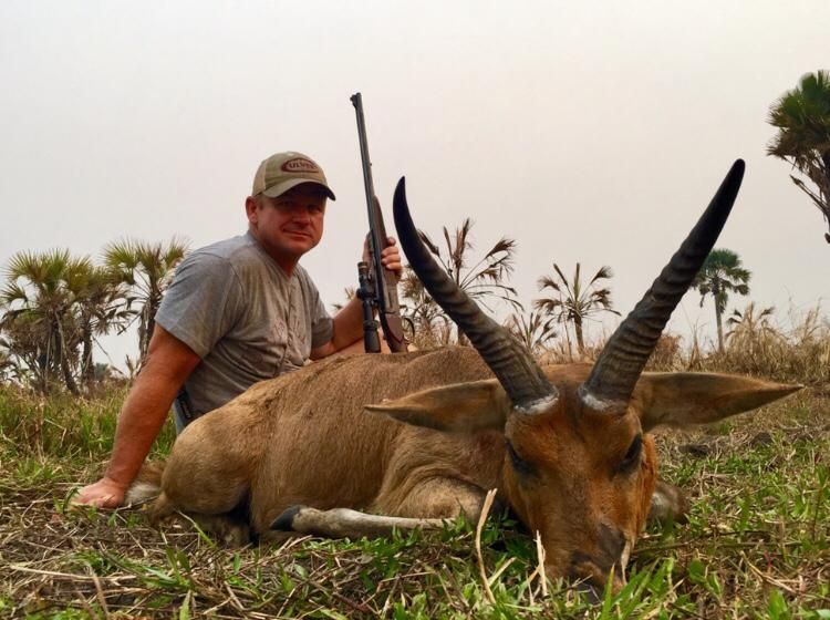 Hunter with a reedbuck ram taken in palm savanna, Zambezi Delta, Mozambique