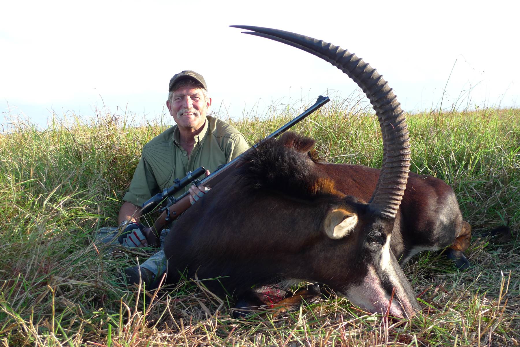 Hunter with a sable bull taken in green grass, Zambezi Delta, Mozambique