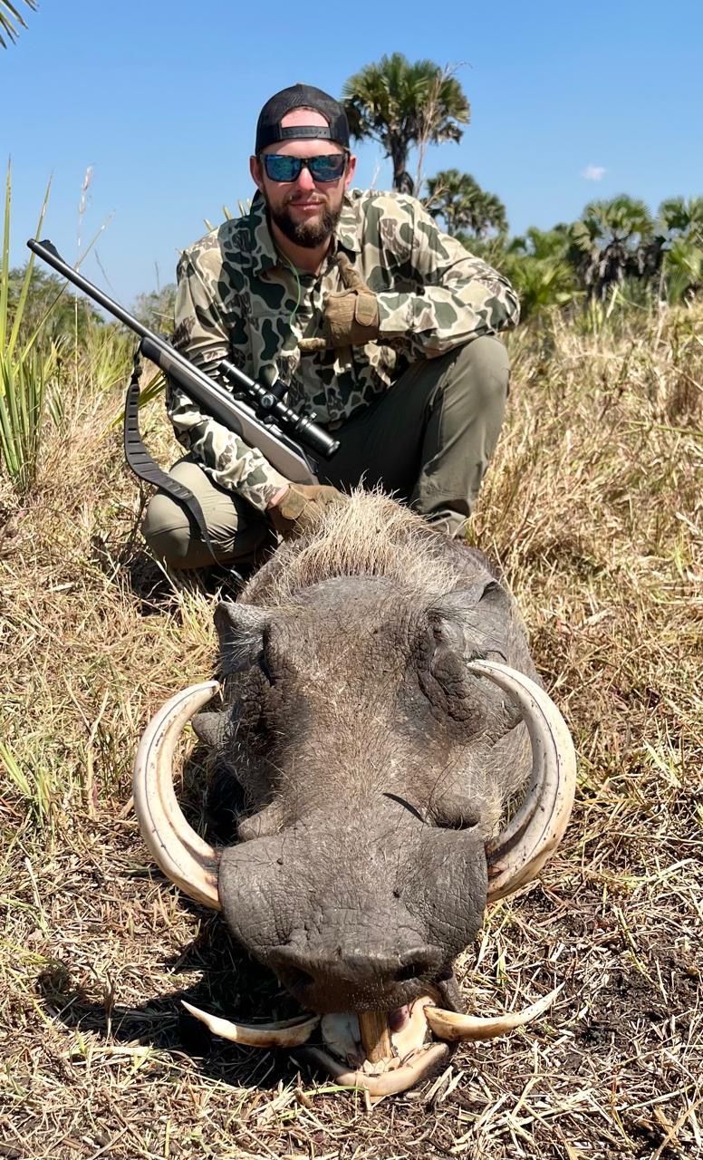 Hunting client with an ivory-tusked warthog boar, Zambezi Delta, Mozambique