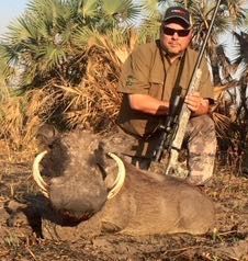 Hunter with a warthog boar taken in palm scrub, Zambezi Delta, Mozambique