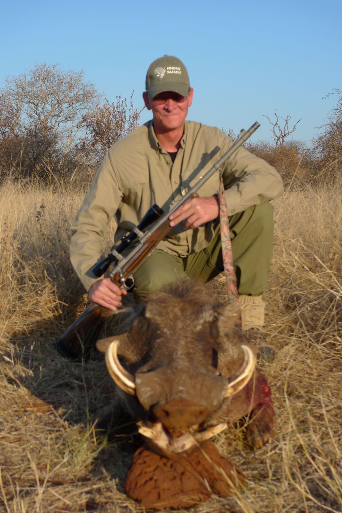 Hunter with his rifle beside a warthog boar, Limpopo, South Africa
