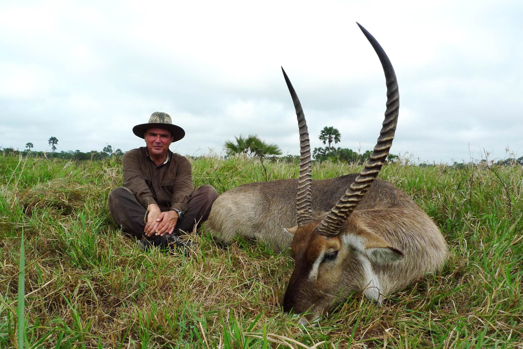 Hunter seated beside a waterbuck bull on the floodplain, Zambezi Delta, Mozambique