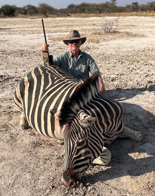Hunter with a Burchell's zebra taken on an open pan, Limpopo, South Africa